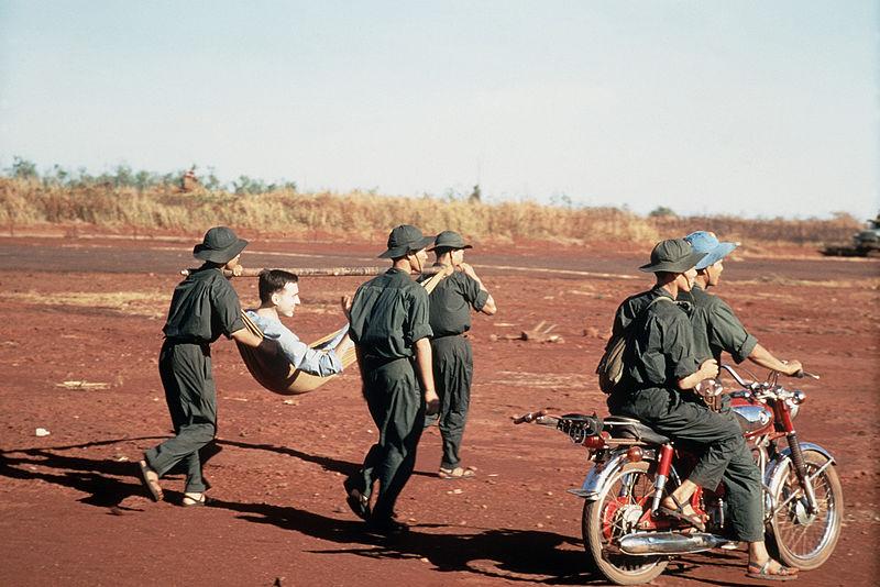 Viet Cong Carry Wounded US POW To Prisoner Exchange, South Vietnam, 1973